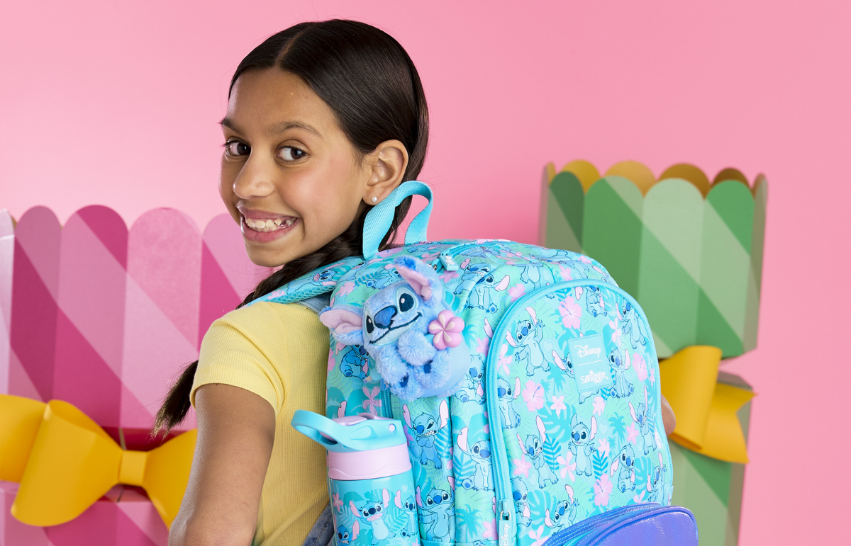 Smiling girl looking back carrying Stitch decorated backpack